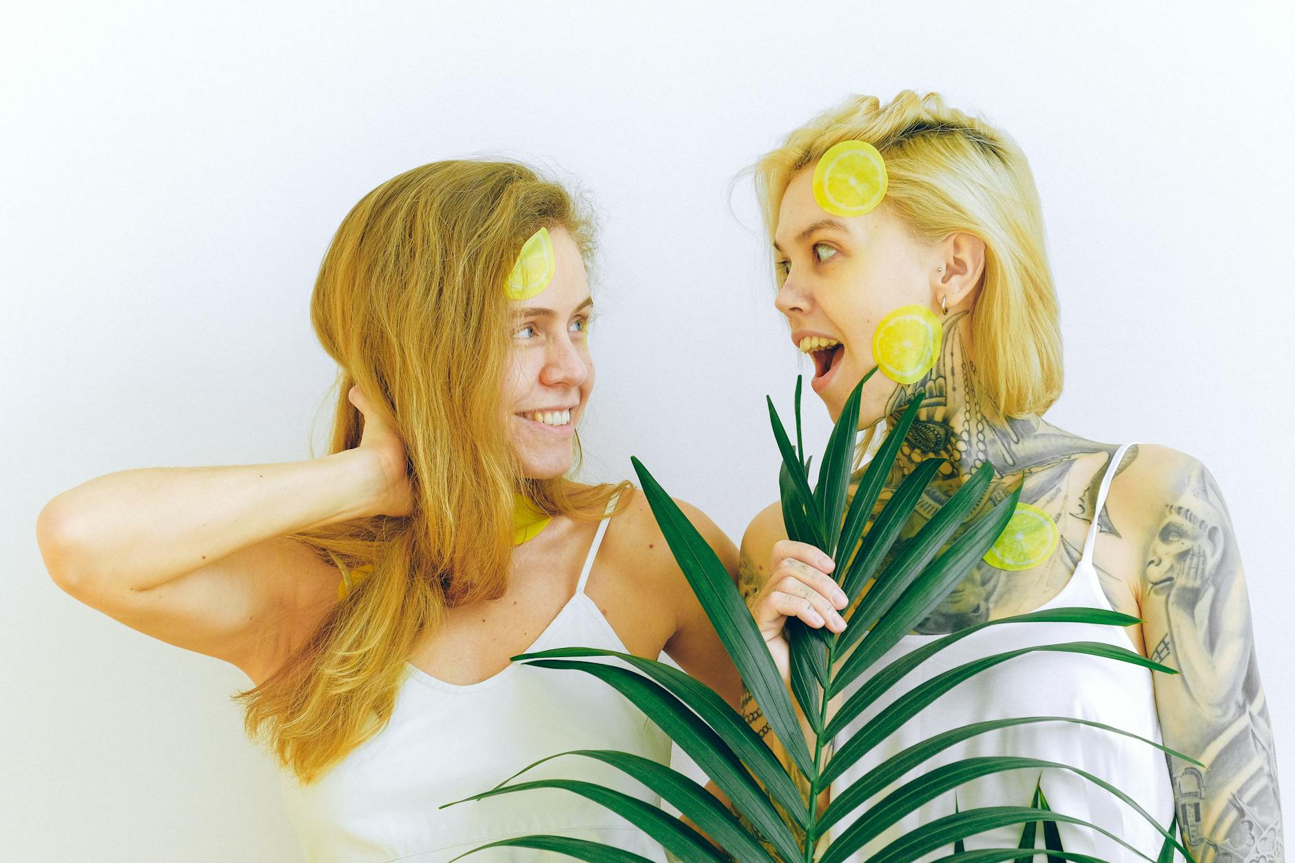 Manos sosteniendo vibradores de silicona rosa y azul contra un fondo pastel