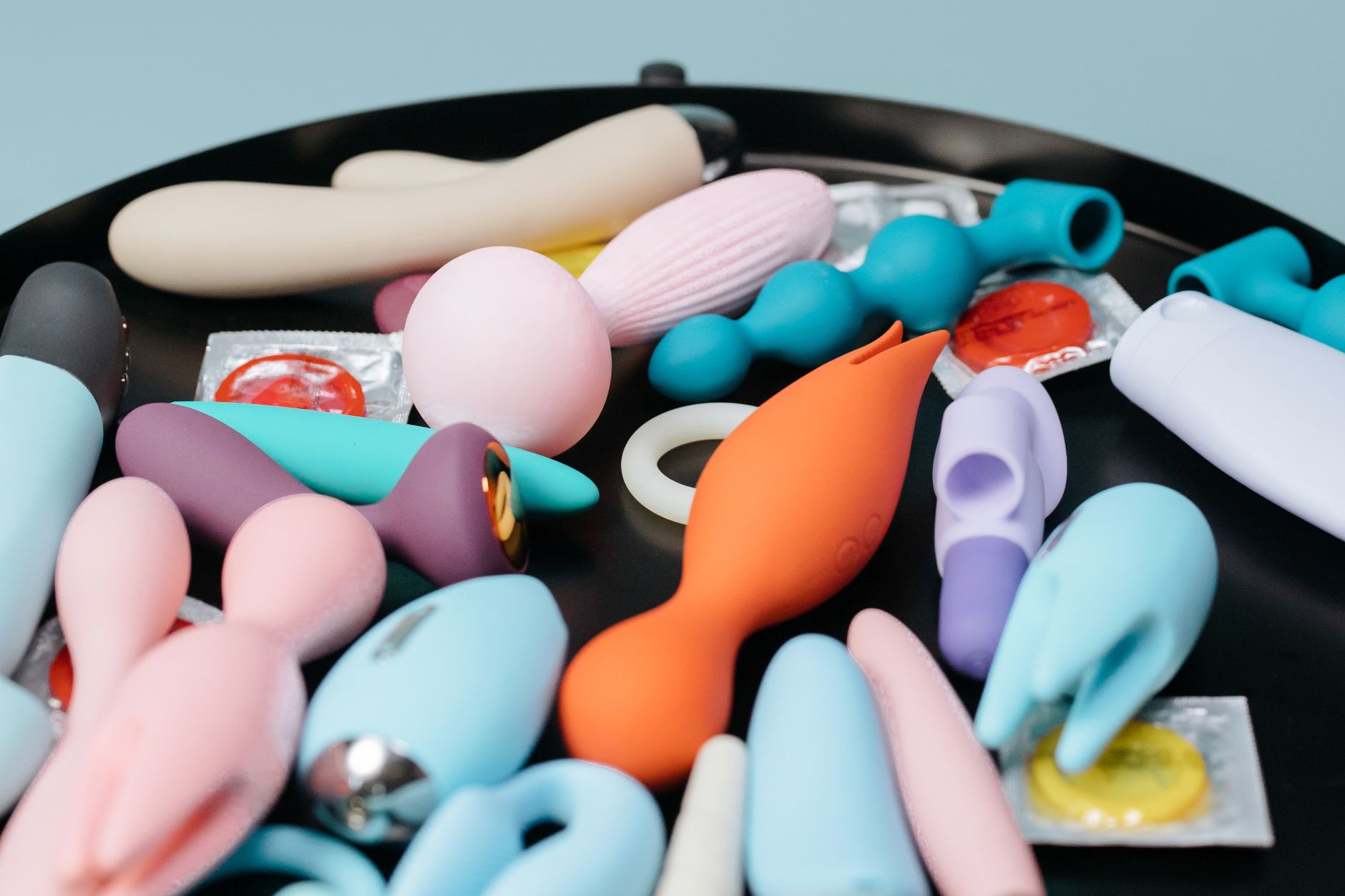 Mujer sosteniendo un vibrador rosa con libros de arte de fondo, enfatizando temas íntimos y personales