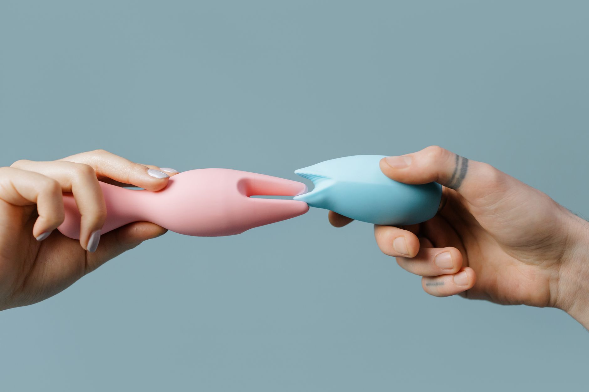 Hands holding pastel-colored silicone toys, illustrating gentle and tender exploration