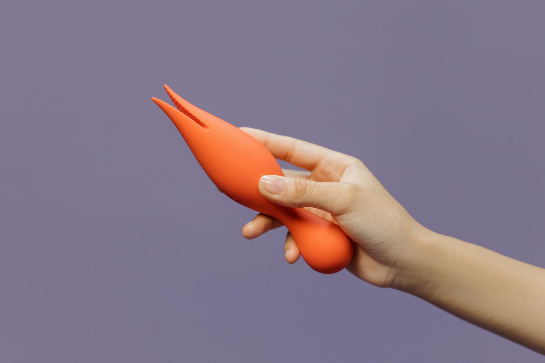 Close-up of a hand holding a Lem vibrator against a minimalistic purple backdrop, showcasing modern sensuality.