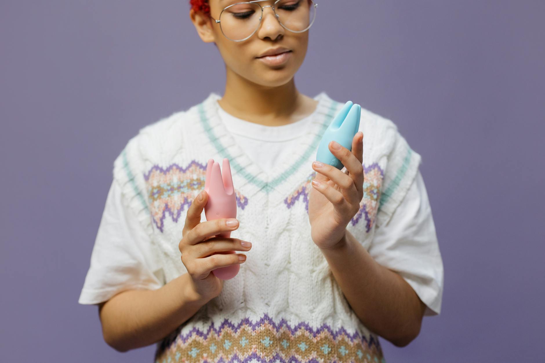 Mujer sosteniendo vibradores de silicona azul y rosa en actitud contemplativa