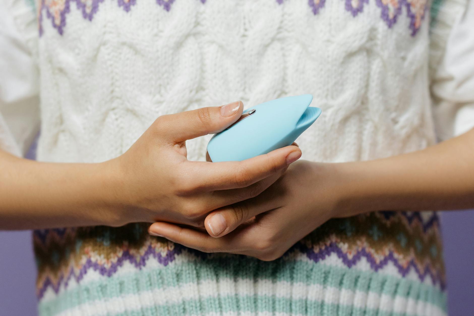 Close-up of hands holding a blue personal massager together, symbolizing shared exploration