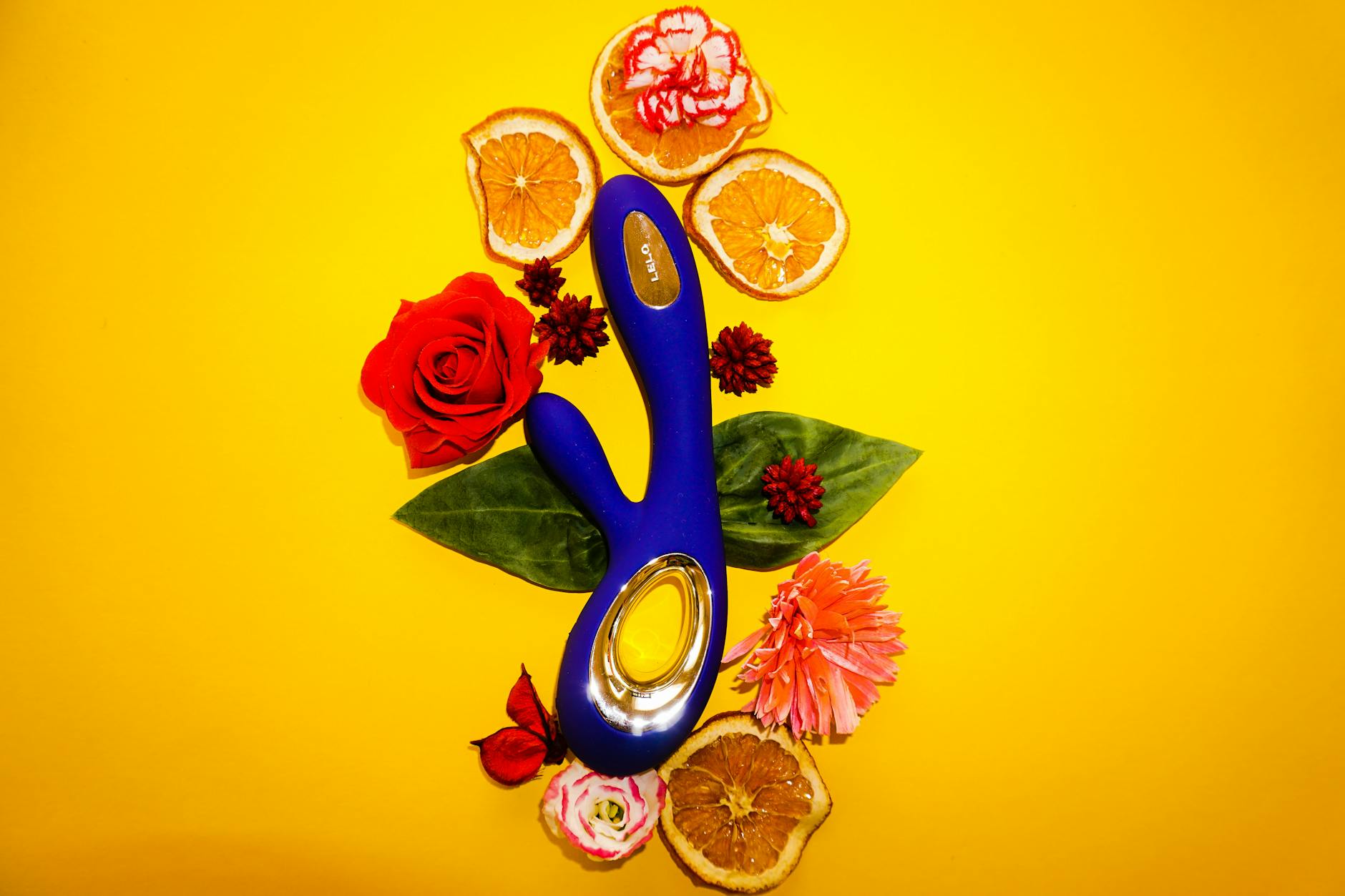 Vibrador de limón azul rodeado de flores y naranjas en fondo amarillo