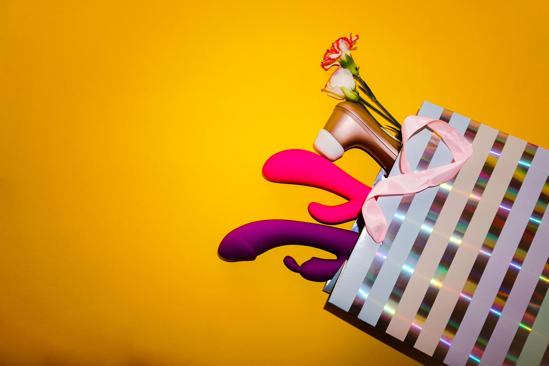 Hand holding a vibrator against a purple backdrop, modern and sensual