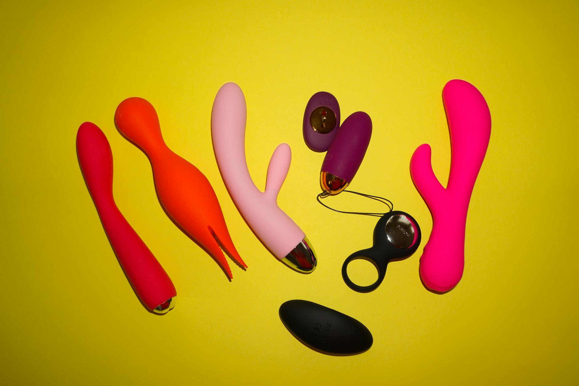 Yellow silicone vibrator surrounded by tropical fruit on a bright yellow background