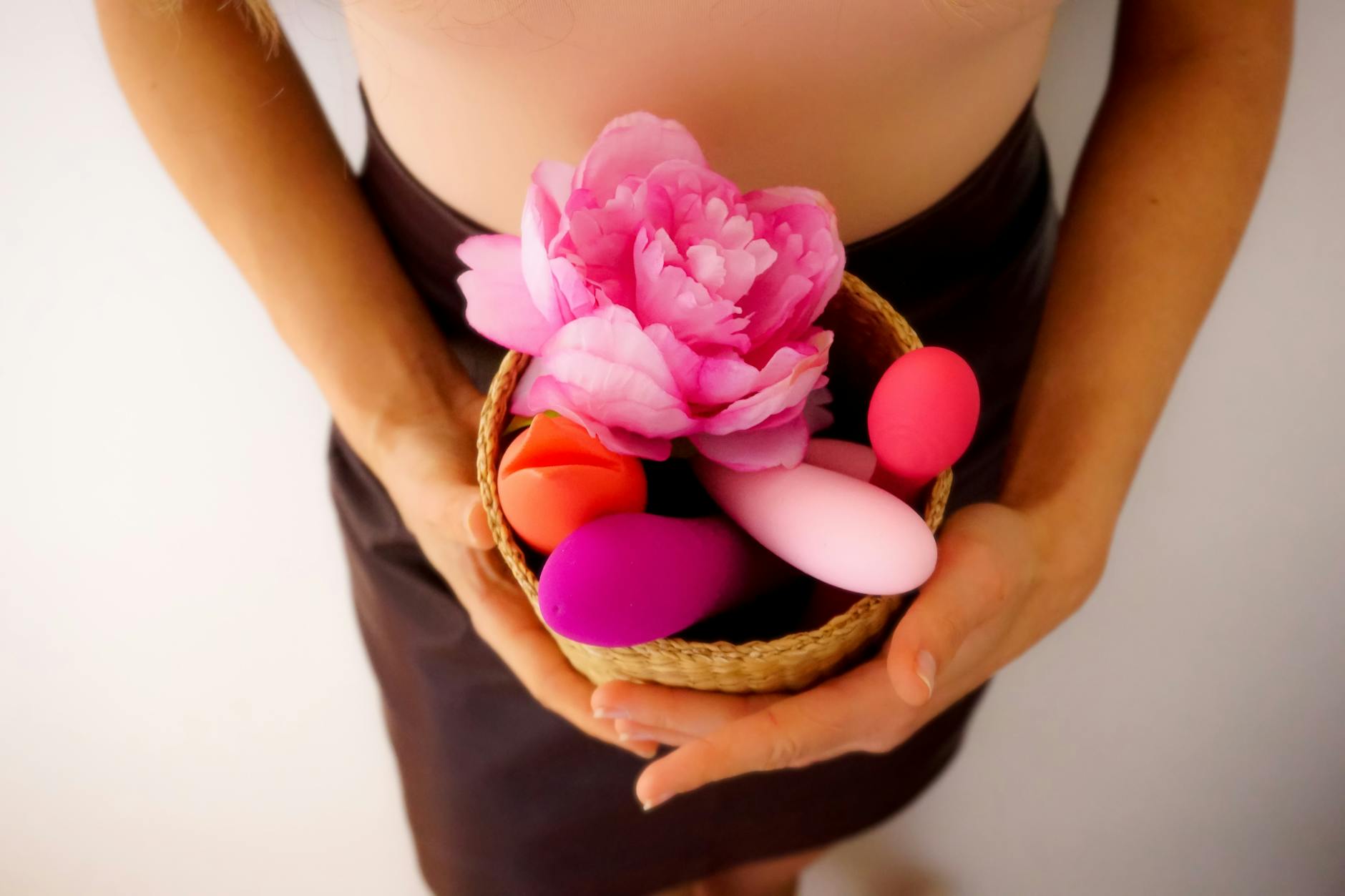 Mujer sosteniendo un vibrador rosa con libros de arte de fondo, enfatizando intimidad y temas personales