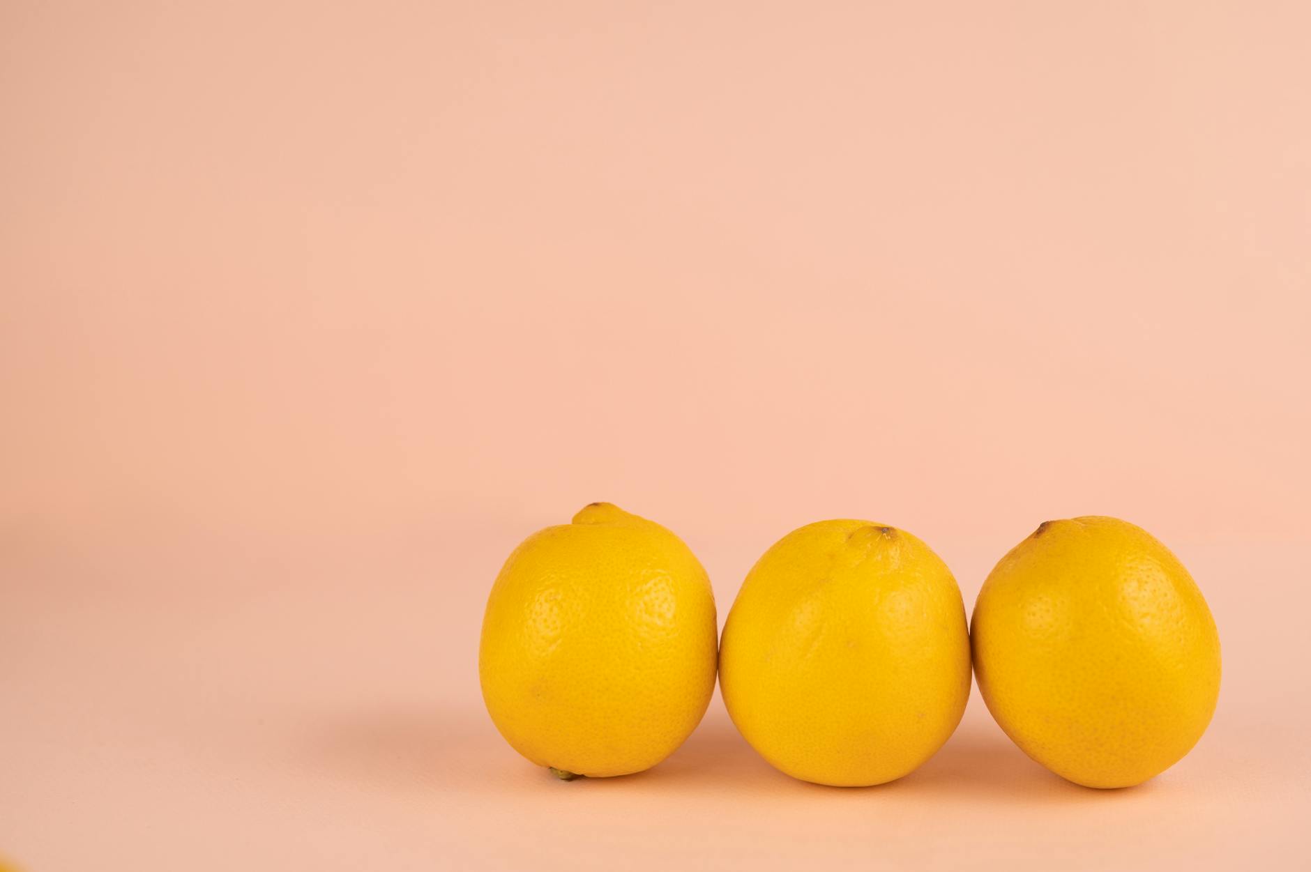 Limones brillantes y maduros dispuestos en fondo pastel, representando el ciclo natural femenino